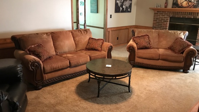 Interior lounge with tan leather sofas, round coffee table, brick fireplace, wooden accents, and world map wall art
