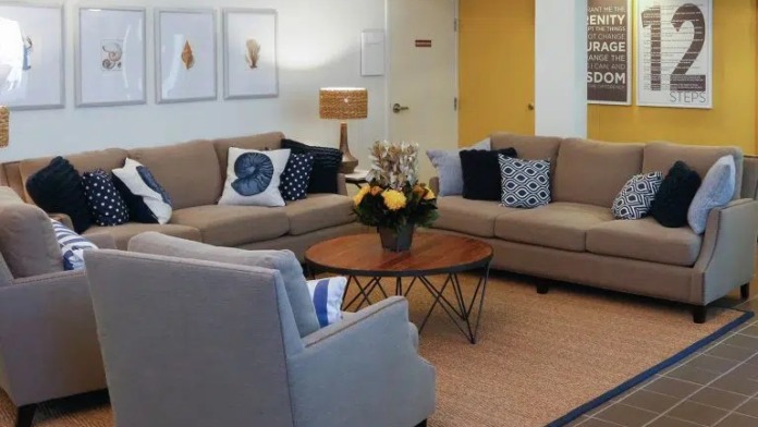 Interior seating lounge with couches, armchairs, inspirational wall text, and framed artwork with natural lighting