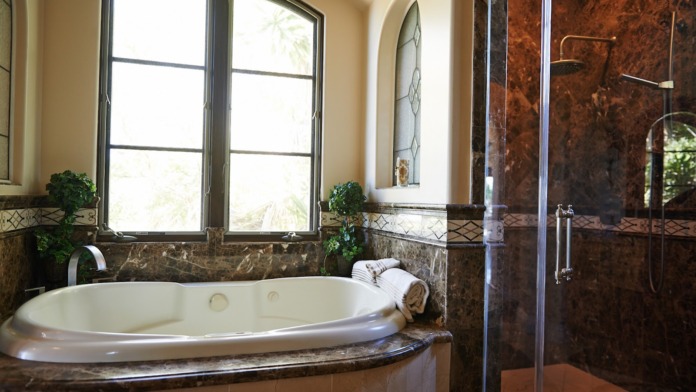 Interior spa bathroom featuring large soaking tub with ocean window views, walk-in shower with marble, and high-end fixtures