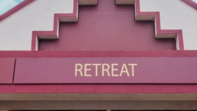 Exterior view of Retreat Behavioral and Mental Health Center showing distinctive pink and white architectural facade with facility signage and entrance doors