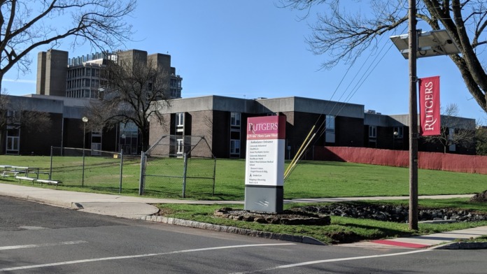 Exterior view of main treatment facility building with modern architecture, Rutgers signage, green lawn, and parking area