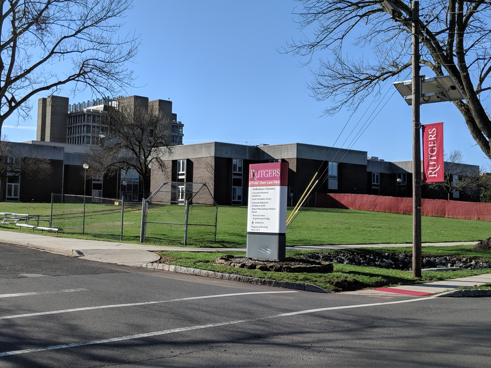 Exterior view of main treatment facility building with modern architecture, Rutgers signage, green lawn, and parking area