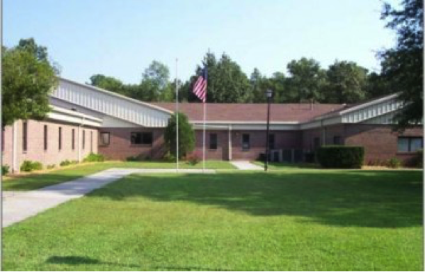 Exterior view of brick behavioral health facility with courtyard, lawn, and American flag