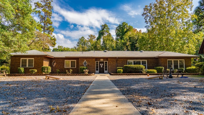 Exterior front facade of brick treatment facility with central entrance, multiple windows, landscaped grounds, and gravel pathway