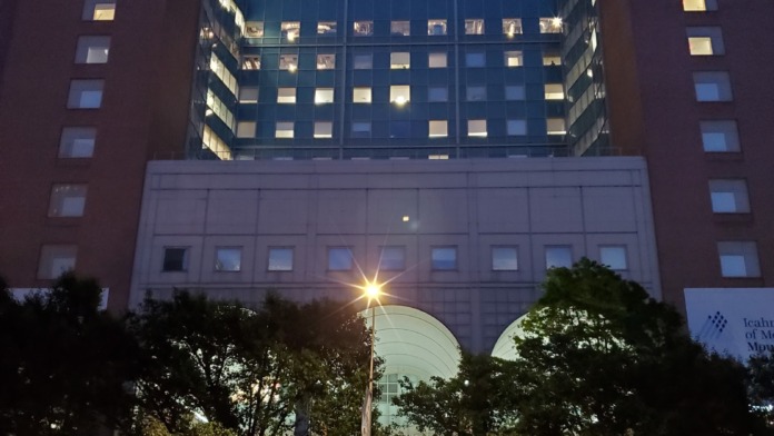 Exterior nighttime view of Mount Sinai West multi-story brick building with illuminated windows and blue sky