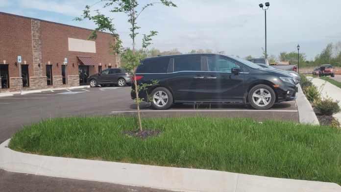 Exterior view of brick facility building with parking area, trees, landscaping, and clear weather
