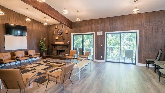 Interior common area with wood paneling, fireplace, leather seating, and large glass doors to outdoor patio