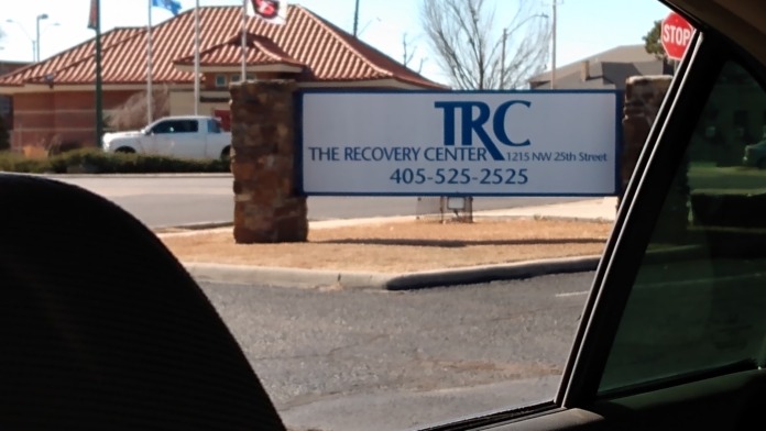 Exterior view from driveway showing The Recovery Center signage with building and flagpoles in background