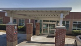 Exterior view of treatment center main entrance with brick columns, covered walkway, and glass entry doors