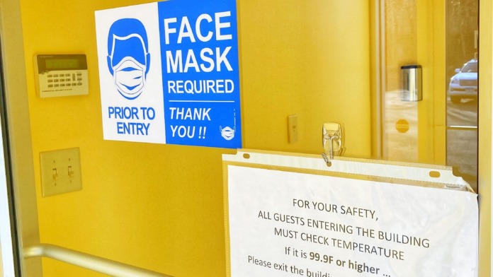 Interior entry vestibule with yellow walls, blue face mask required signage, and safety health notice