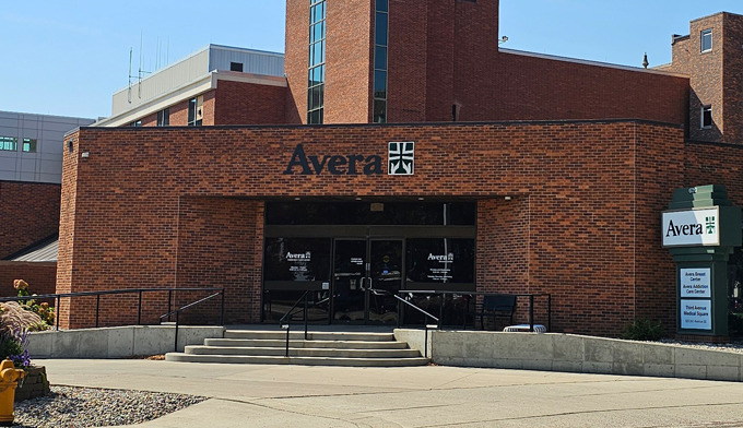 Exterior of Avera Addiction Care Center showing brick building with main entrance, Avera logo signage, and accessible entry ramp