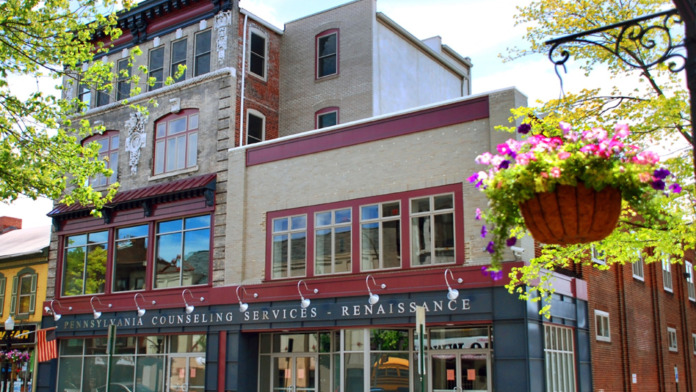 Exterior view of Pennsylvania Counseling Services Renaissance location showing storefront with maroon and dark trim, large windows, and brick building facade