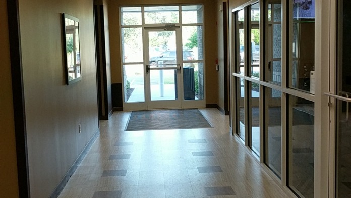 Interior entrance hallway with MyHealtheVet signage on ceiling, glass doors, and modern flooring