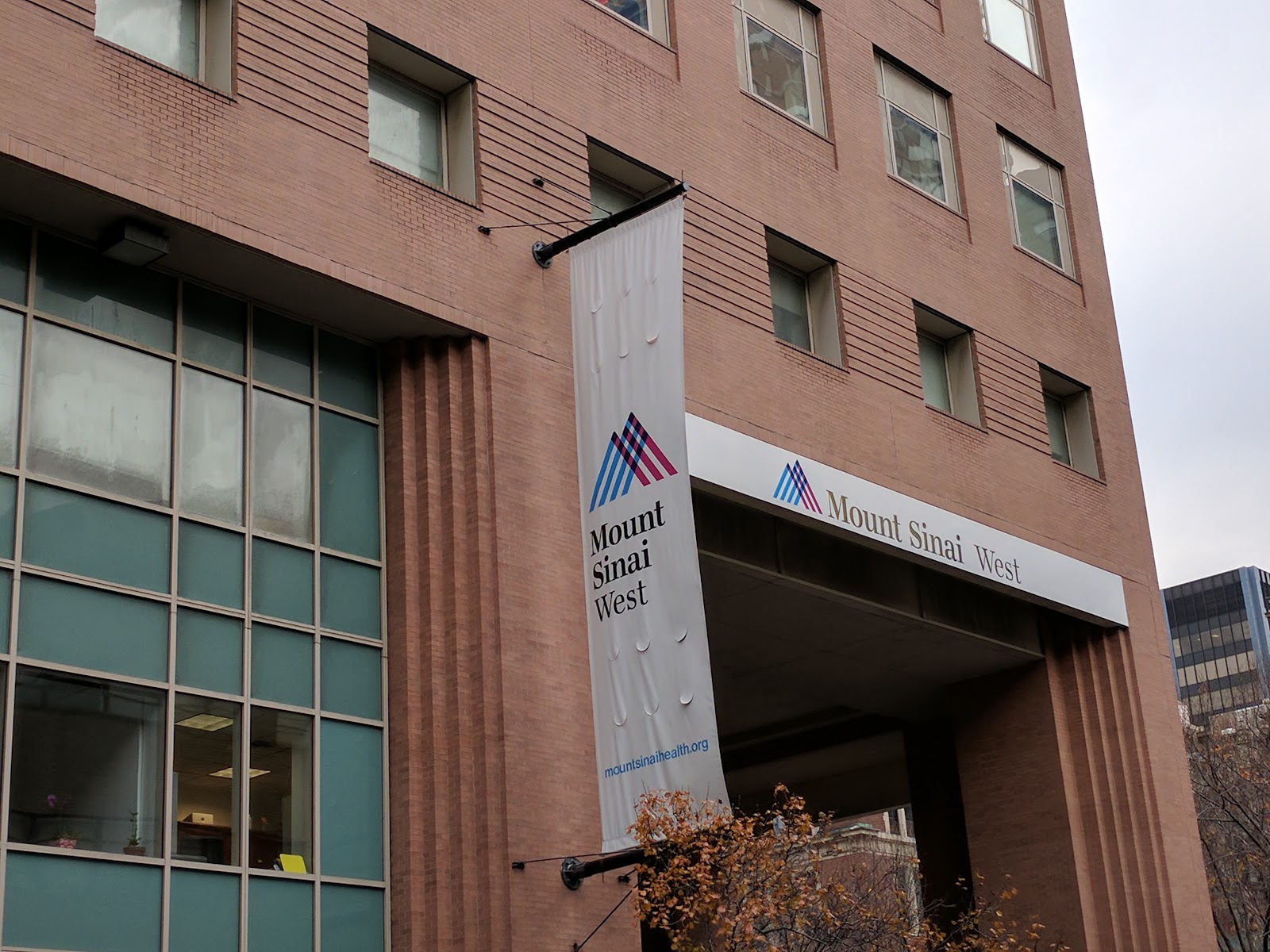 Exterior view of Mount Sinai West building entrance with white signage and brown brick facade