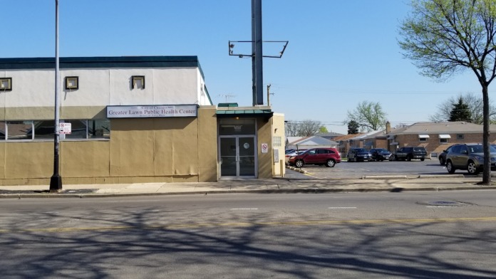 Exterior front view showing main entrance doors, facility name signage, and multi-story building with parking area