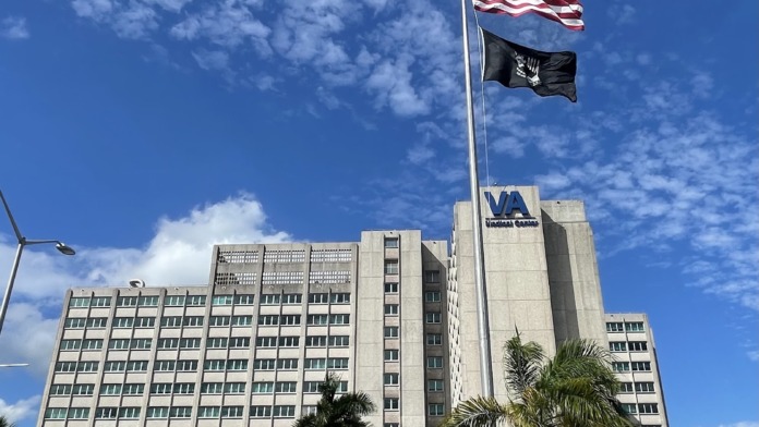 Exterior view of multi-story VA Medical Center building with flags and main entrance area