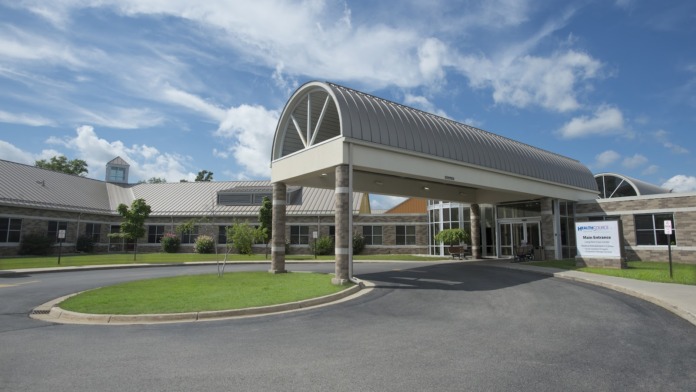Exterior entrance with architectural portico, landscaped grounds, and facility signage visible