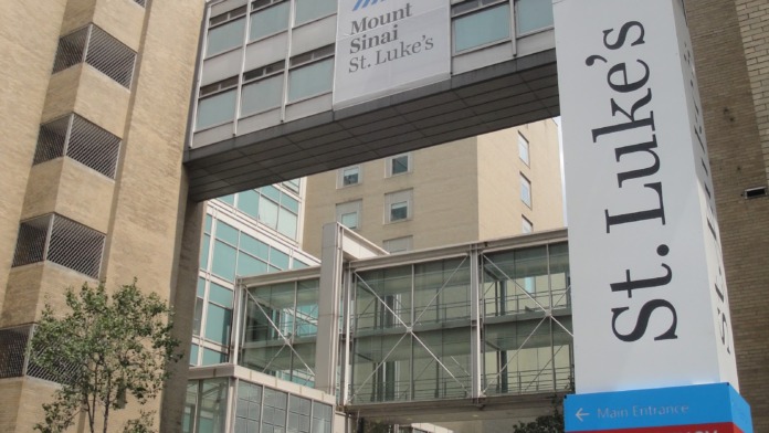 Exterior view of main entrance with emergency signage, wayfinding signs, and vehicle access area
