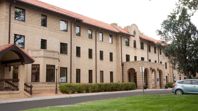 Exterior front elevation showing brick construction, arched entry, main entrance with canopy, and manicured landscaping