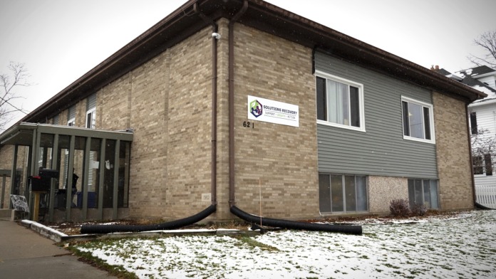 Exterior view of brick and siding two-story facility building with covered entrance, signage, and snow-covered grounds.