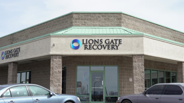 Exterior view of brick and stone recovery facility with green-framed entrance doors and parking lot