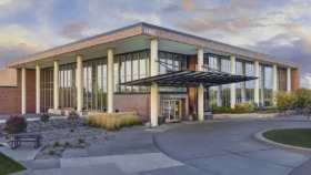 Exterior view of modern treatment facility with brick and glass construction, covered entry portico, and manicured landscaping at main entrance