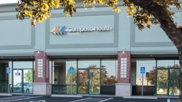 Exterior view of Compass Health Network treatment center with main entrance, glass doors, and illuminated signage