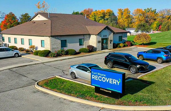 Exterior view of Fort Wayne Recovery treatment center building with main entrance, parking area, and blue facility sign