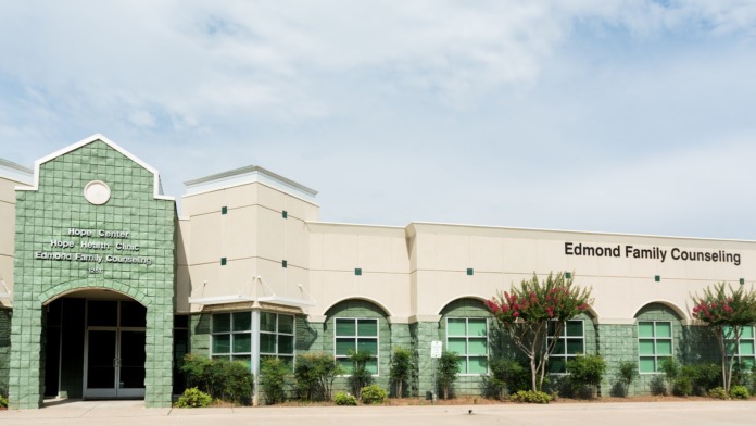 Exterior front view of Edmond Family Counseling building showing main entrance with green tile accents, signage, and landscaping