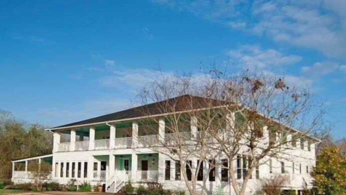 Exterior of two-story white treatment facility with green accents, columns, wraparound porches, and manicured landscaping