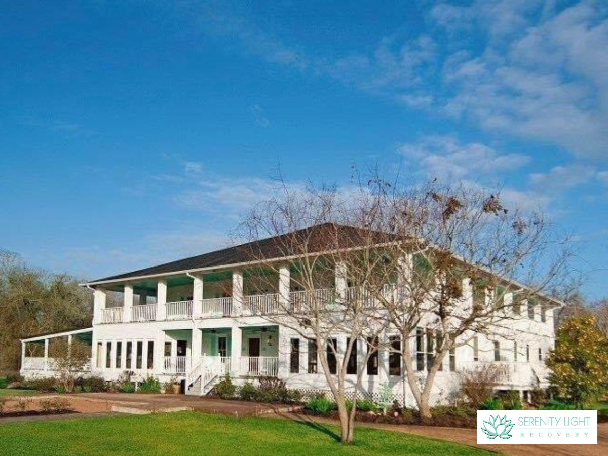 Exterior of two-story white treatment facility with green accents, columns, wraparound porches, and manicured landscaping