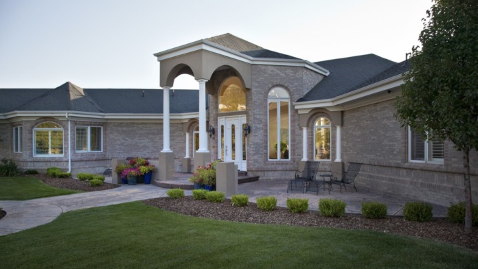Exterior view of treatment center showing brick construction, white columns, arched entrance, landscaped grounds, and patio seating area