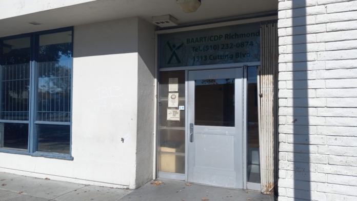 Exterior view of treatment facility entrance with white and brick facade, glass doors, and signage