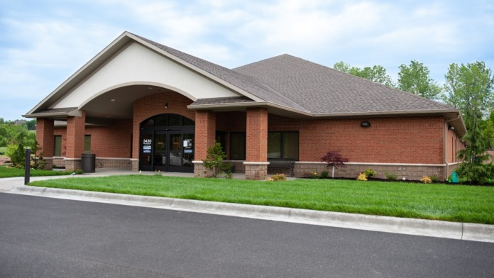 Exterior view of brick treatment facility with covered entrance, manicured landscaping, and parking area