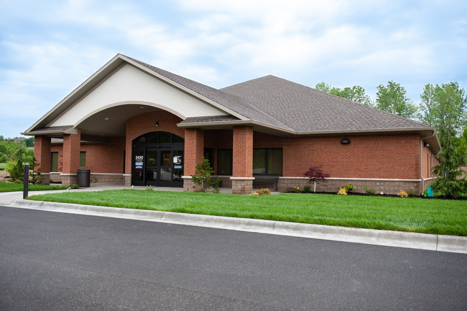 Exterior view of brick treatment facility with covered entrance, manicured landscaping, and parking area