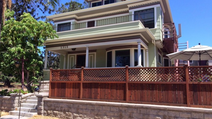 Exterior front view of Turning Point Home at 1315 25th Street showing two-story cream and brown building with covered porch, wooden lattice fence, and landscaping