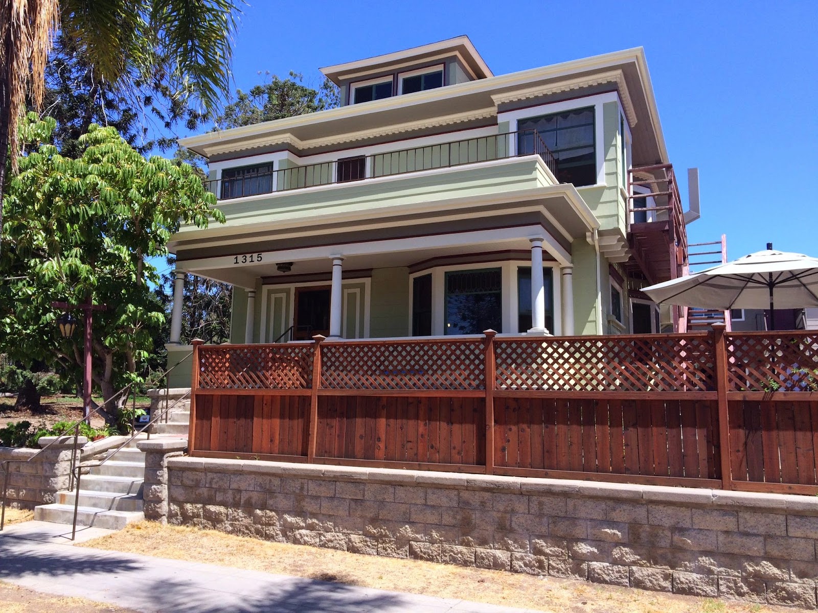 Exterior front view of Turning Point Home at 1315 25th Street showing two-story cream and brown building with covered porch, wooden lattice fence, and landscaping