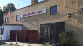 Exterior view of Bridgeway, Inc. brick building with main entrance, flagpole, and front signage at 620 West Grand Avenue