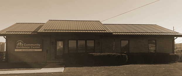 Exterior view of Community Guidance Center brick building with metal roof, landscaping, and entrance signage