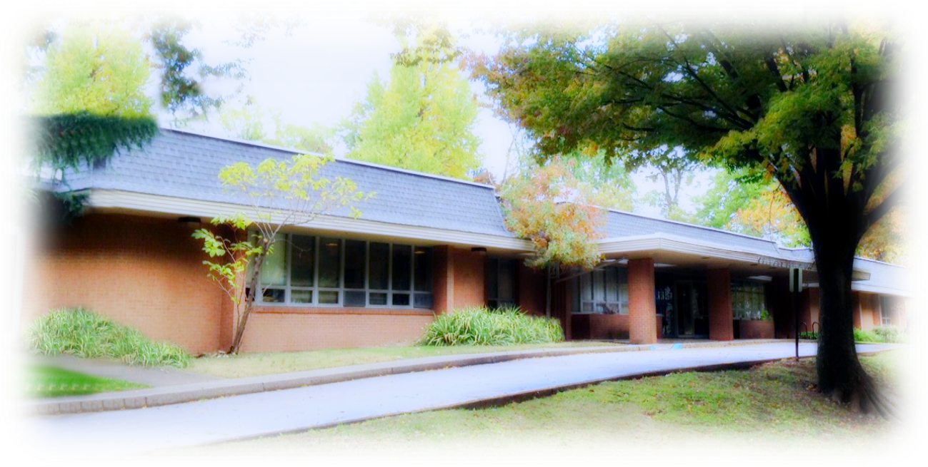 Exterior view of brick treatment center building with covered entrance, large windows, and manicured landscaping
