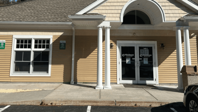 Exterior front entrance of treatment facility with columned portico, double glass doors, and tan siding