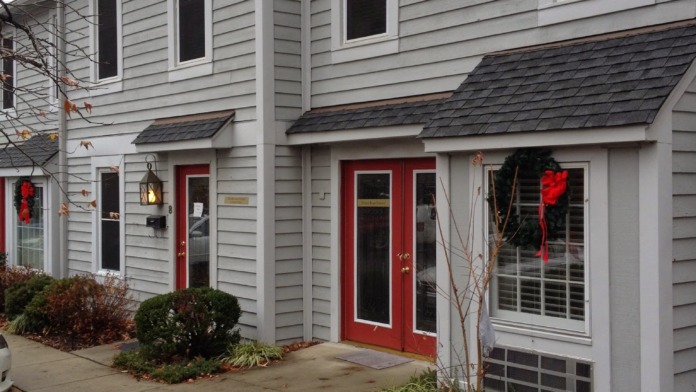 Exterior view of two-story treatment facility with gray siding, red doors, and landscaped grounds