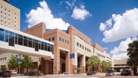 Exterior view of Saint Joseph Medical Center showing brick facade, main entrance with arched openings, and palm tree landscaping