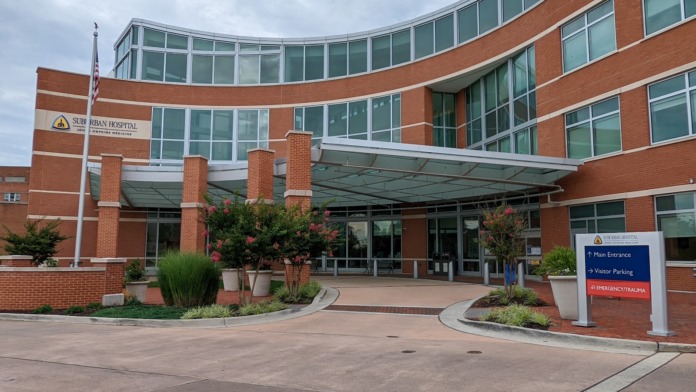 Exterior view of brick hospital building with main entrance canopy, landscaped grounds, and facility signage