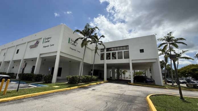 Exterior view of North Shore Medical Center white building with Surgery Center signage, palm trees, and covered entrance area