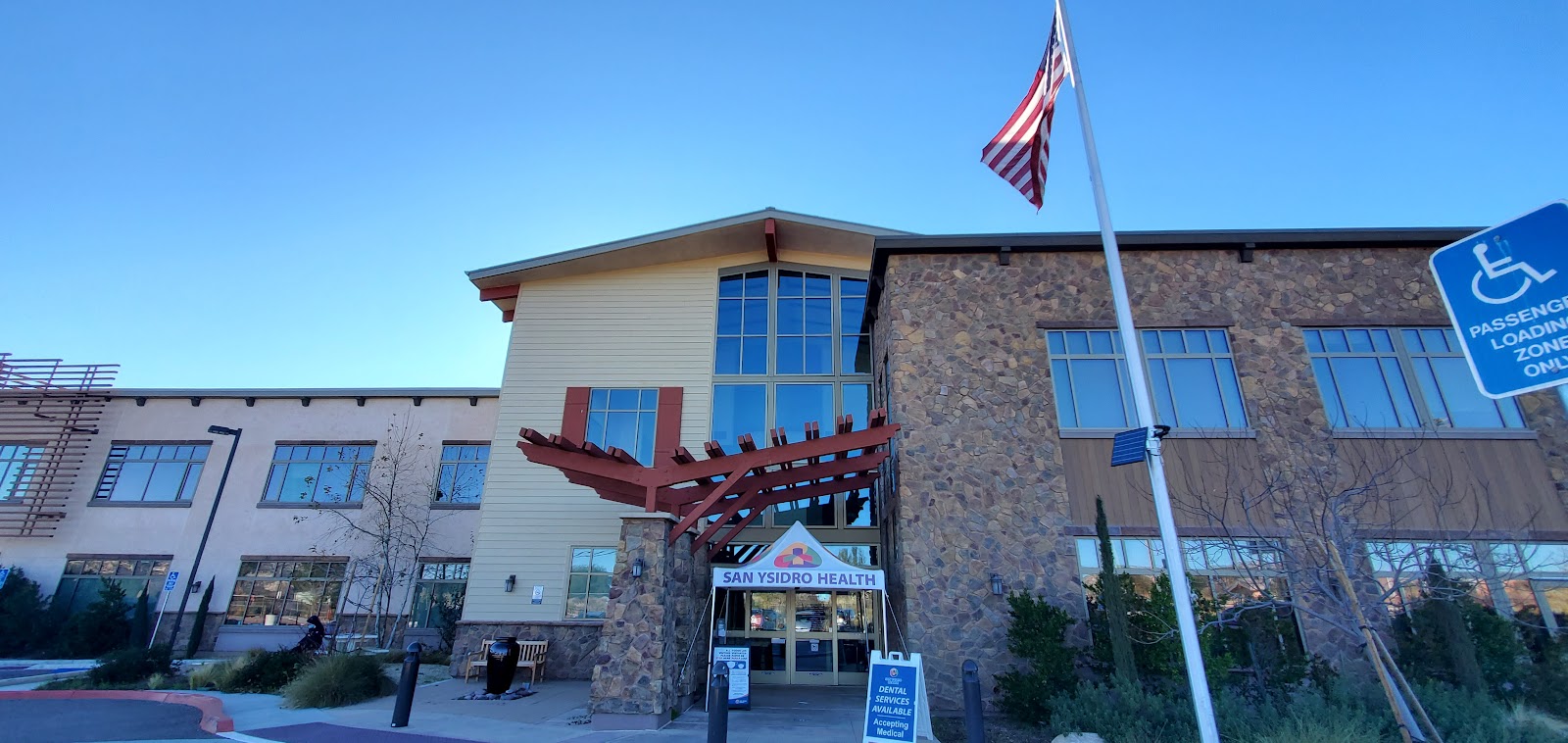 Exterior front entry with stone and siding facade, covered entrance, and accessible parking area