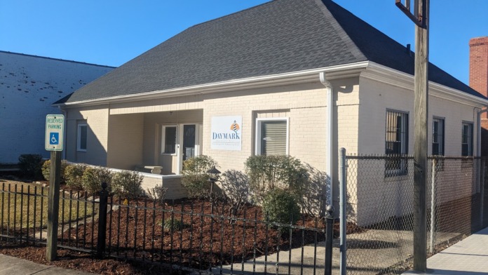 Exterior of treatment facility showing beige brick single-story building with metal railings, entrance porch, and landscaped grounds