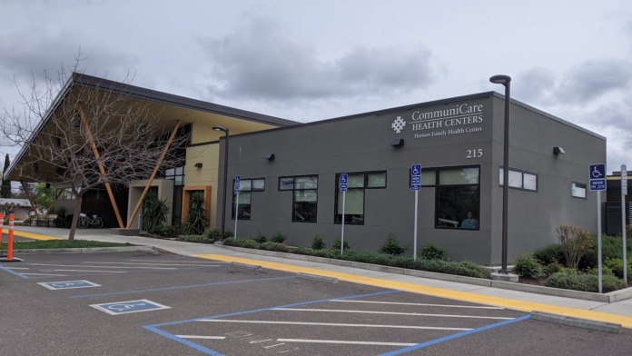 Exterior view of Communicare Health Centers Hansen Family Health Center building with parking lot, accessible parking spaces, and entrance signage