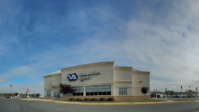 Exterior view of VA Outpatient Clinic building with main entrance, landscaping, and parking lot with clear signage