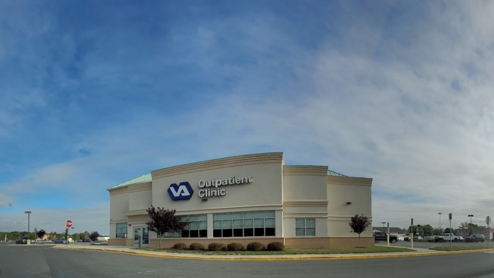 Exterior view of VA Outpatient Clinic building with main entrance, landscaping, and parking lot with clear signage